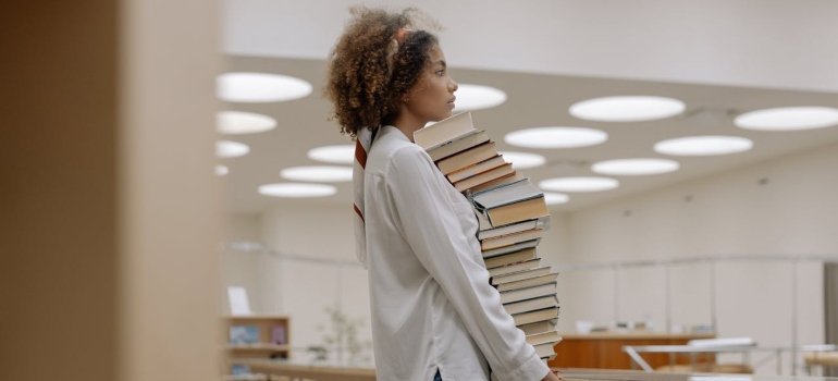 Person carrying books and thinking about the renting short-term storage units