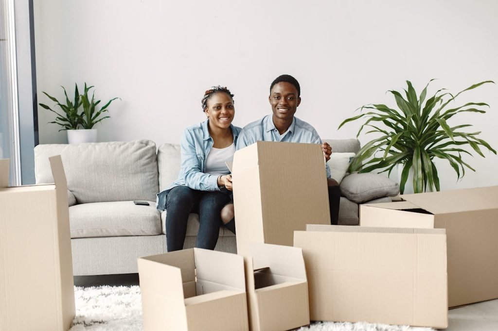 A Young Couple Sitting in a Living Room Full of Cardboard Boxes and thinking about how to pack sharp and oddly shaped items