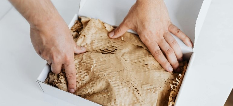 A woman packing her stuff with a paper bag.