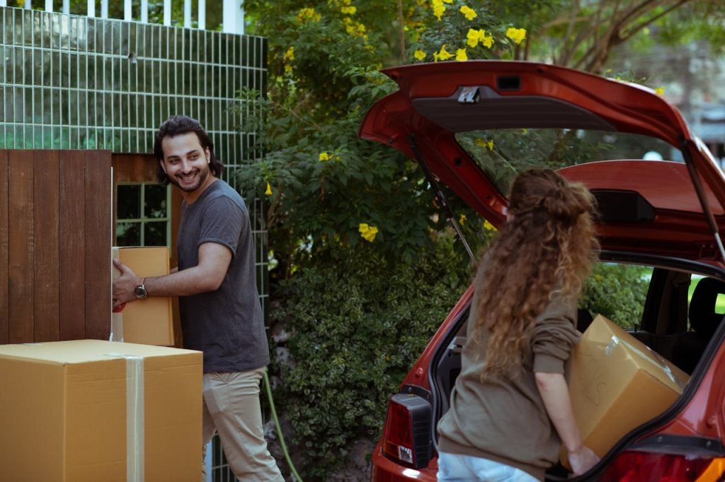 Couple moving boxes from car trunk to new house