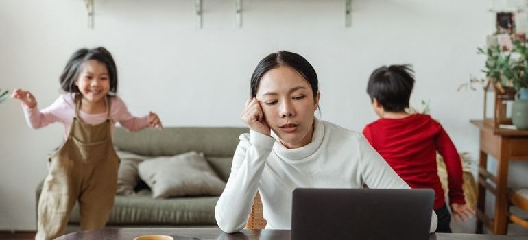 Stressed out mother using her laptop to help with moving for a job with a family.
