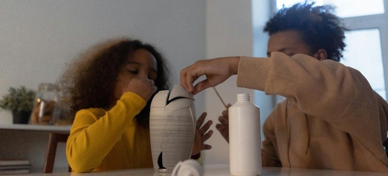 Two kids gluing a broken vase together, a small project that reflects how to Fix and Update Before Renting Your Alexandria Apartment.