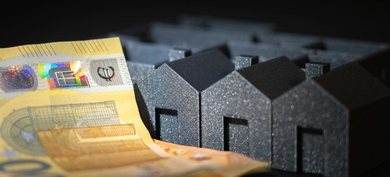 Small black house models with a euro banknote, representing housing costs and Cost of Living and Moving Expenses in Stafford County.