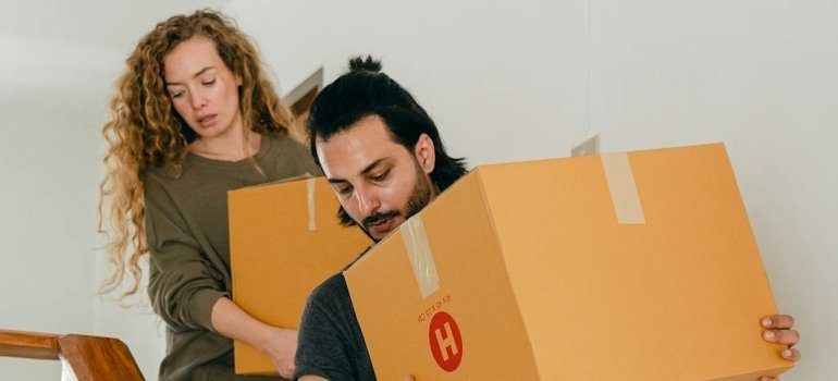 Couple carrying boxes down the stairs