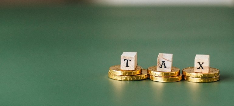 Wooden blocks spelling TAX on stacked coins, symbolizing financial planning and tax considerations.
