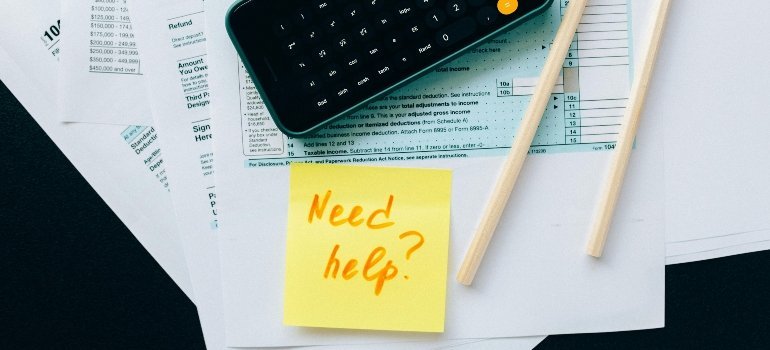 A calculator and sticky note on tax forms, symbolizing support for financial and tax planning.