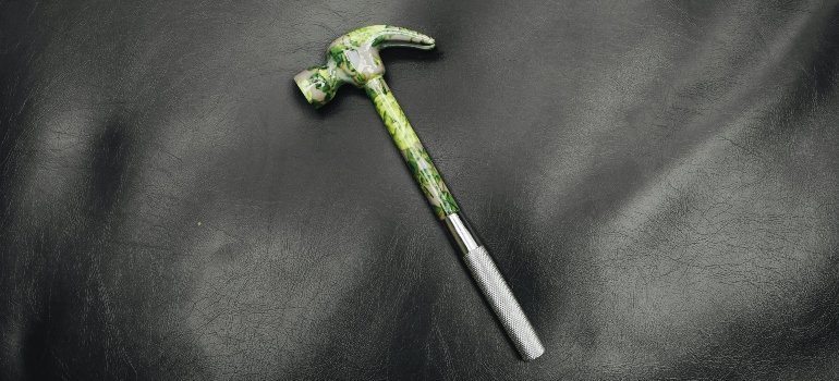 Green and silver hammer on a black background, symbolizing simple home projects before renting out a place.