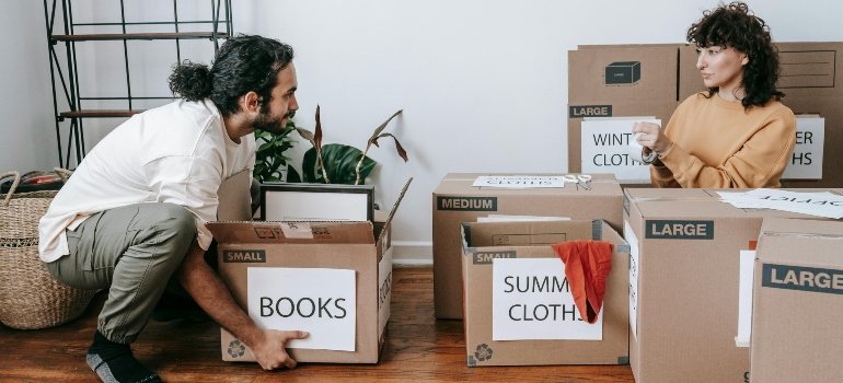 People organizing labeled moving boxes to prepare for unpacking in a new home.