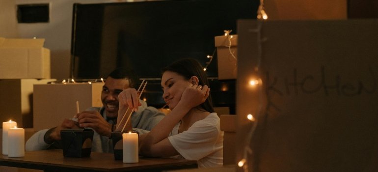 Couple eating by candlelight in a new home filled with moving boxes after Moving from Alexandria to Waldorf.