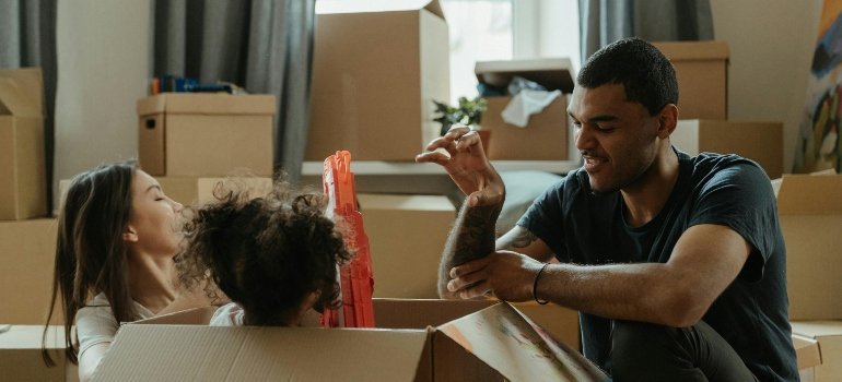 A happy family sitting among moving boxes while unpacking in their new home.