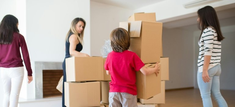 Family arranging cardboard boxes in an empty living room before settling into a new home.