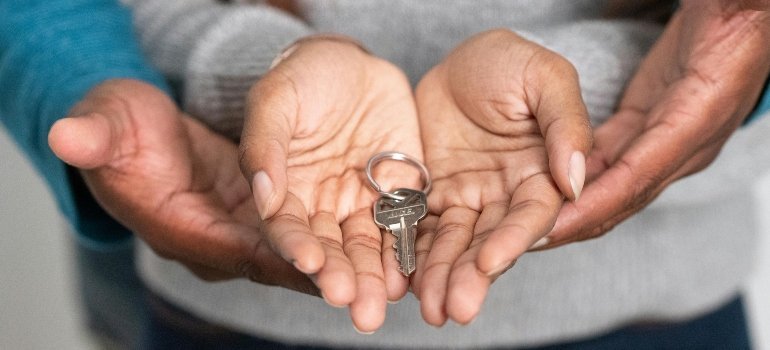 Close-up of hands holding a house key, symbolizing the start of homeownership.