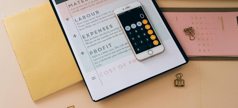 A smartphone with a calculator app placed on a pricing formula sheet for budgeting to Live Comfortably in Maryland.