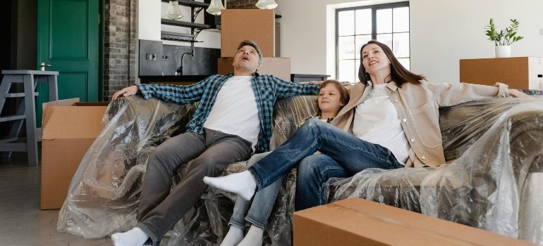A happy family resting on a couch surrounded by moving boxes, symbolizing First-Time Homeowners in Virginia.