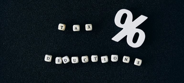 Wooden cubes spelling “tax deductions” beside a white percent symbol — financial planning before you Move Across Virginia.