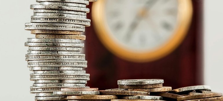 A pile of coins in front of a clock symbolizing saving time and money for a Move From New Jersey to Maryland.