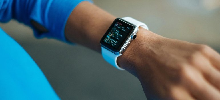 A close-up of a person using a smartwatch to monitor schedule and moving day progress.