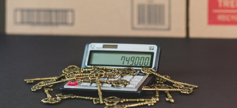 Golden keys placed on a calculator used for estimating moving expenses and household budget.