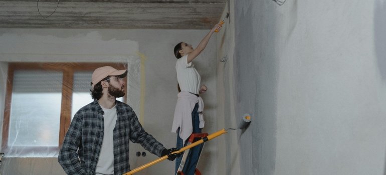 A couple painting their new home together, preparing the walls for their future.