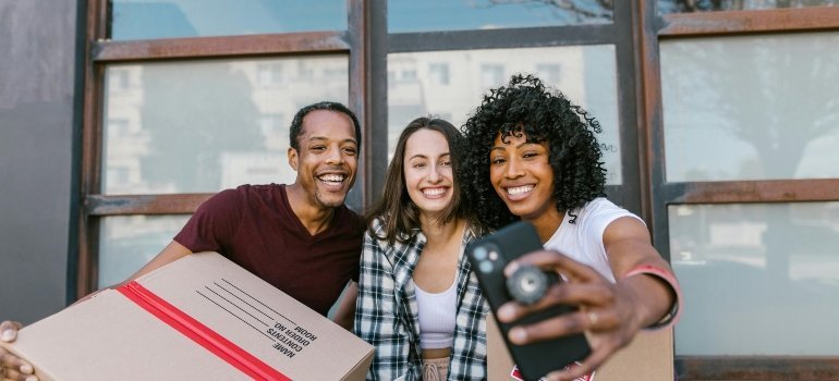 people taking a selfie while holding boxes
