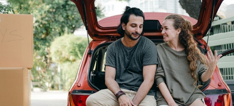a boy and a girl sitting on the car and talking to each other