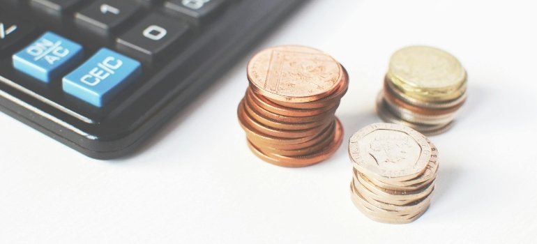 Stacks of coins and a calculator displayed as budgeting examples for Comparing Self-Storage Facilities in Alexandria.