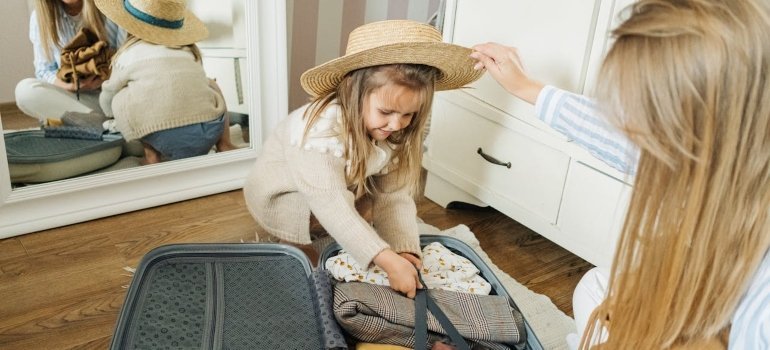 Child and adult packing a suitcase