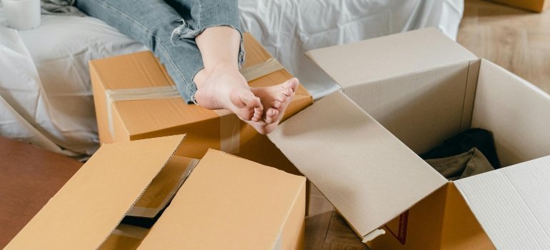 Person relaxing with bare feet among open cardboard boxes after a long packing session.