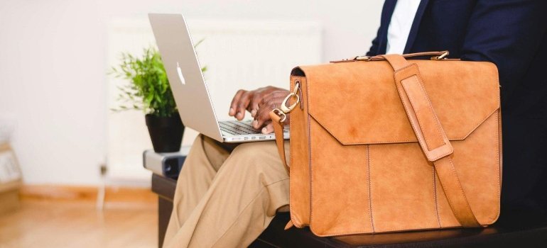 A professional working on a laptop with a briefcase beside them, highlighting how Businesses Benefit from Storage Rentals for added space.