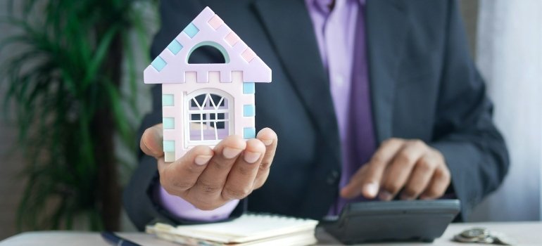 Person holding a house figurine