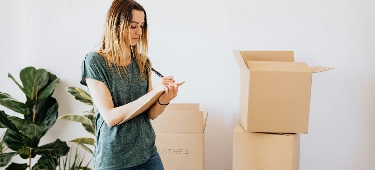 Glad woman writing down notes while packing