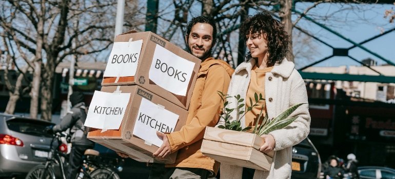 A couple moving out carrying boxes and plants during a short-distance move from Gaithersburg to Clinton