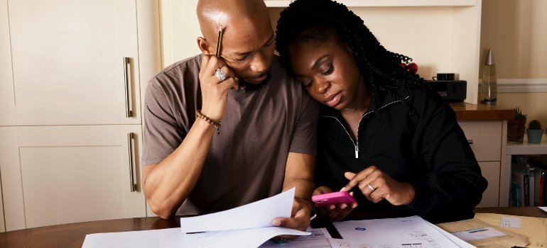 Couple Sitting by Table Calculating Expenses