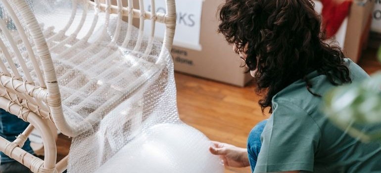 Woman wrapping a chair for storage after learning the benefits of short-term storage services.