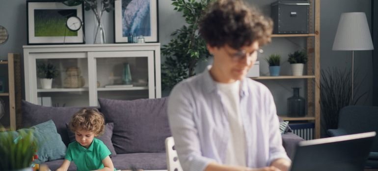 Woman looking up moving trends in Maryland on her laptop while her son plays in the background.