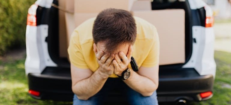 Man sitting in the back of a car and worrying about falling for moving scams.