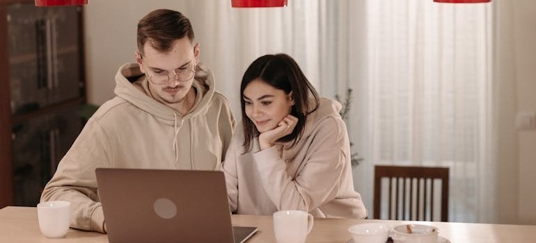 Couple sitting at a table and researching moving scams on a laptop.
