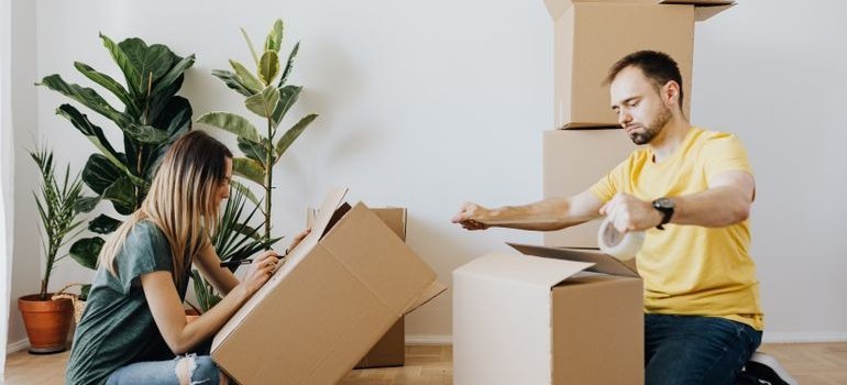 Two people packing moving boxes safely to help with preventing moving injuries.